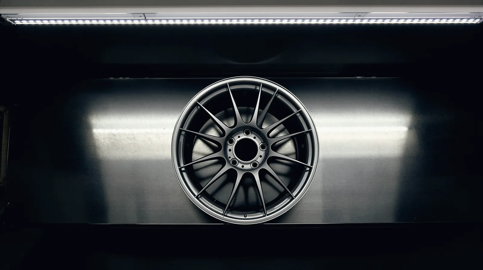 A forged wheel lying on a steel workbench, seen from above
